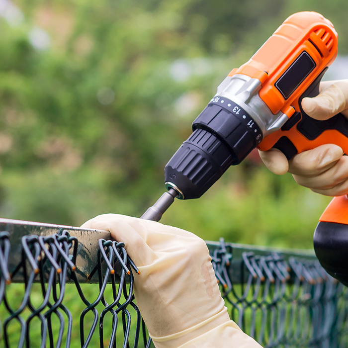 contractor hands close up with drill repairing chain link fence calera ok